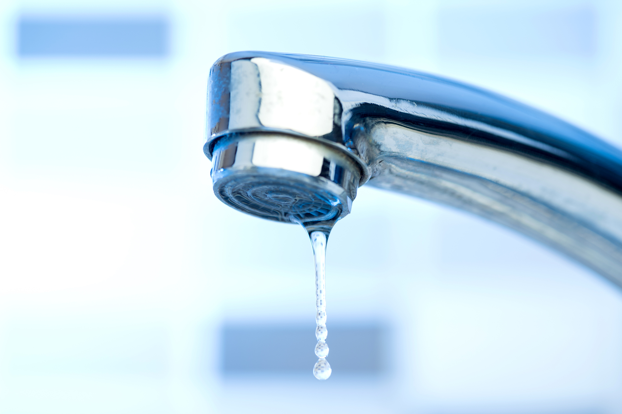 A silver faucet with water dripping out.