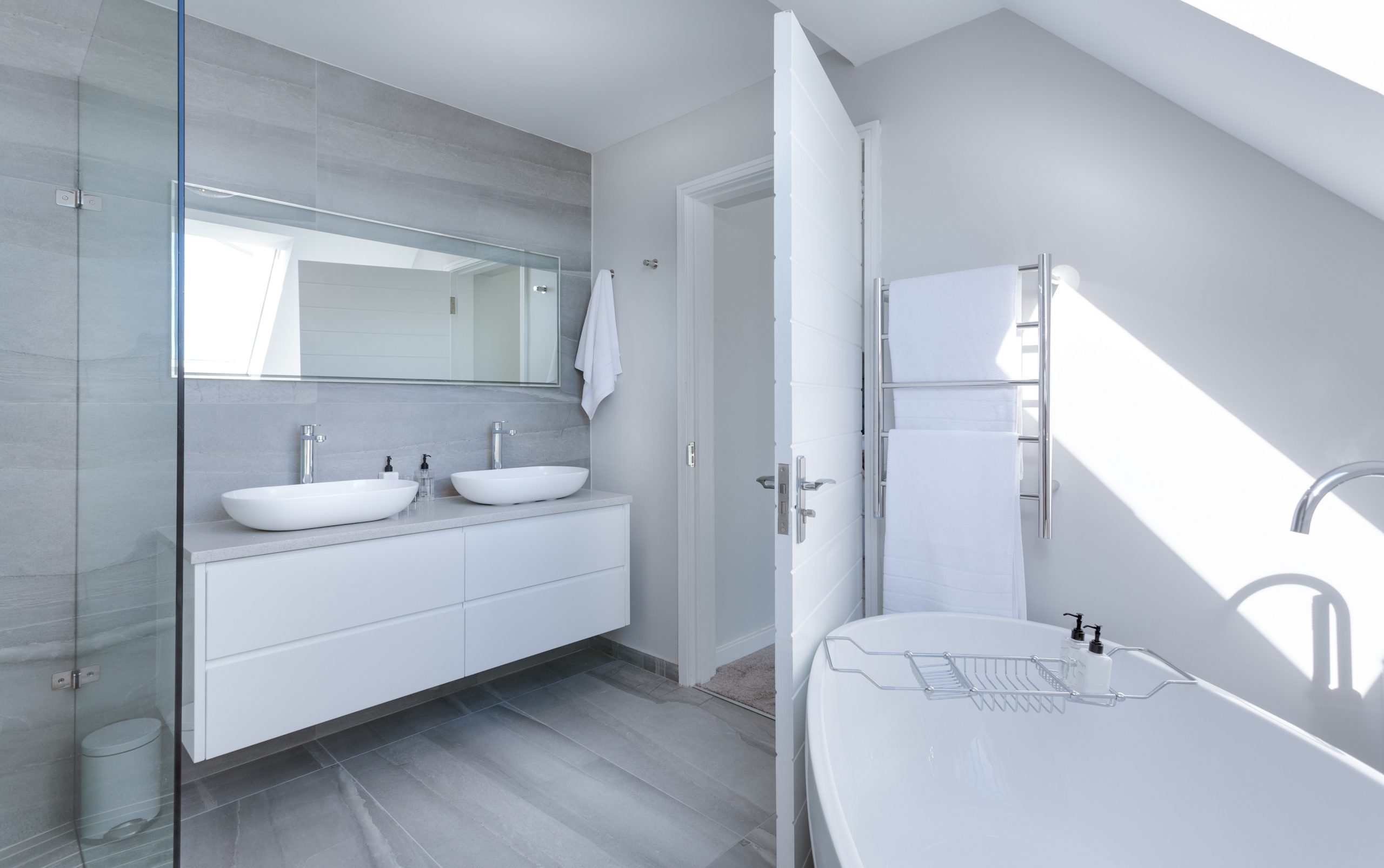 Modern white bathroom with standalone tub and double sink vanity.