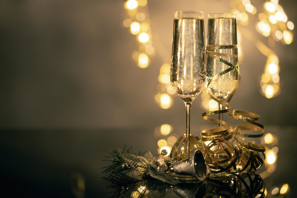 New Years photo: Two glasses of champagne surrounded by gold holiday decor.
