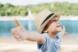 boy outside with arms open and smiling